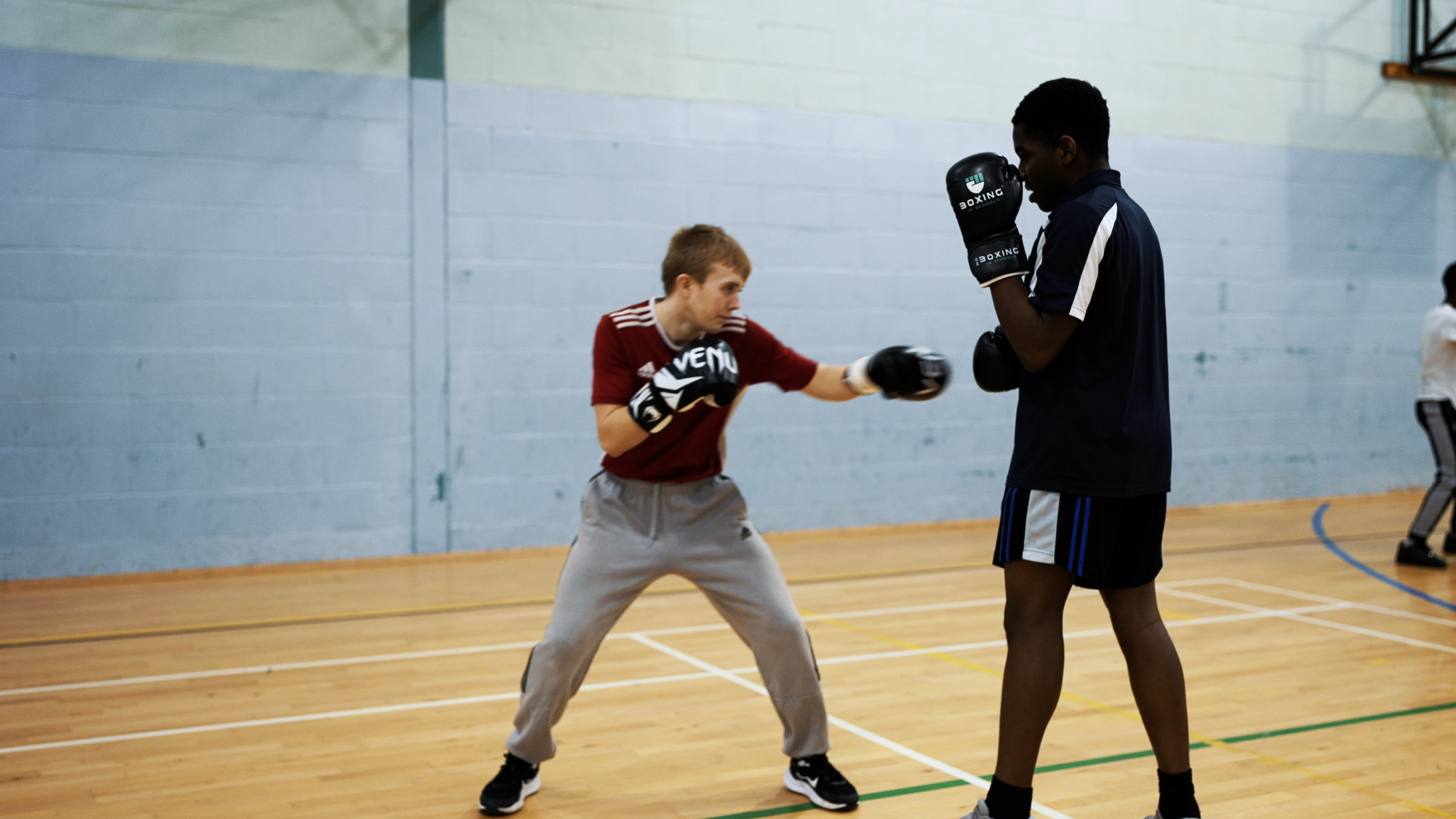 A coach training youth in boxing techniques in a community sports setting